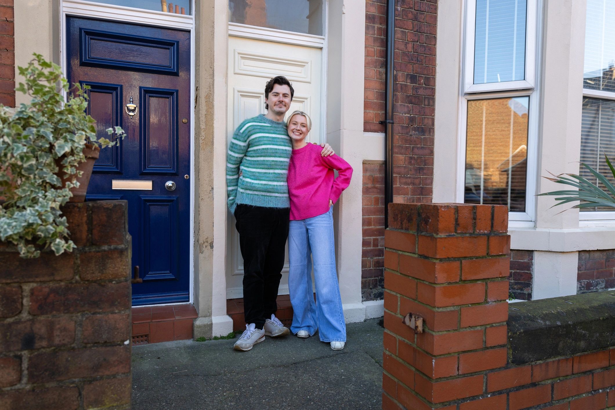 Happy homeowners standing outside their home